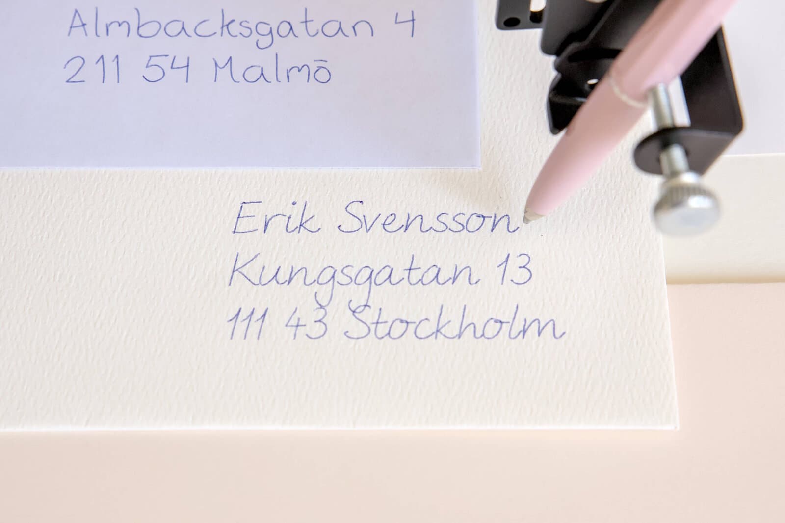 En penna skriver en adress på ett kuvert